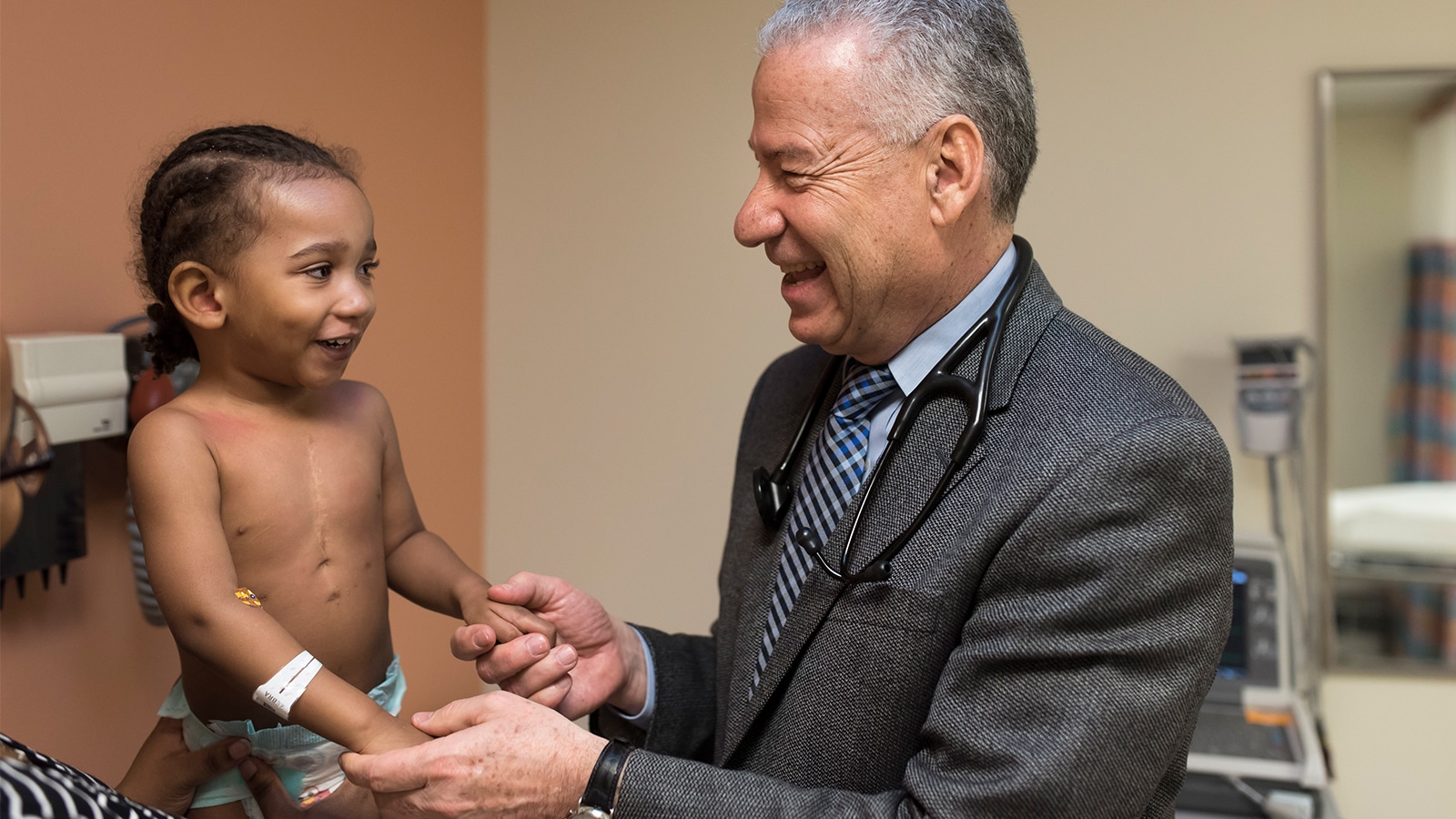A doctor at NYU Langone providing care for a young boy. They are both looking at each other and smiling