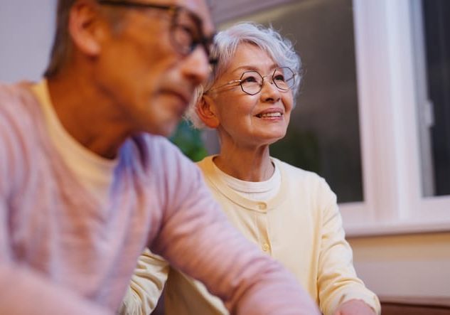 A senior couple attentively listens to a professional therapist during a counseling session in a warmly lit setting. The supportive environment highlights the importance of open communication, emotional well-being, and professional guidance in relationships and mental health.