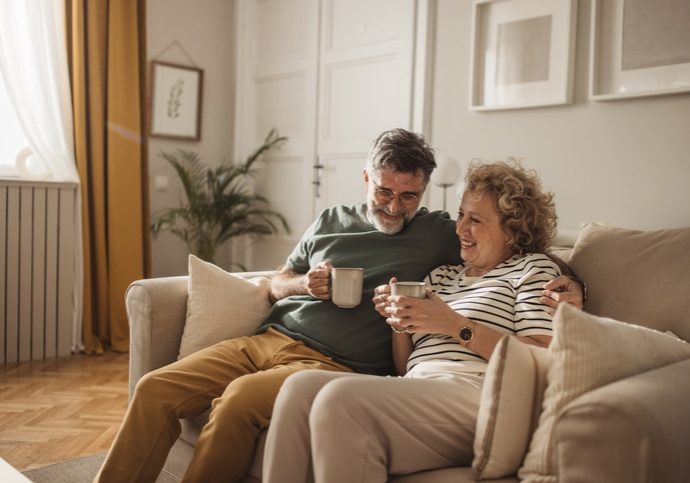 Mature couple at home, spending relaxed day together. Drinking coffee or tea and talking.